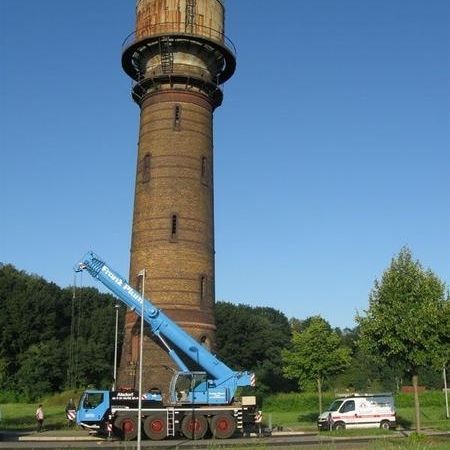 Ein Turm steht im grünen, davor ein Kran