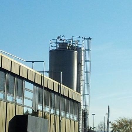 Firmengebäude mit Tank auf dem Tauben sitzen